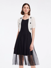 a lady in a white crocheted cardigan and black midi organza vest dress